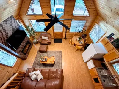 Cozy A-frame great room with fireplace, vaulted ceilings, and bright windows