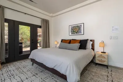 Large primary bedroom with king-size bed, 55" smart TV, separate entrance to back porch with hot tub, and full-length mirror. 