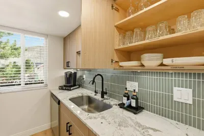 Bright kitchenette with quartz counters, green tile, and a coffee station.