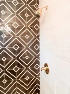 Brass fixtures are enhanced with the constrasting vintage black tiles.