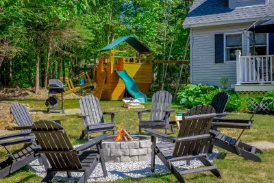 Outdoor entertainment with a wood firepit, gas grill, children's playset and an assortment of outdoor lawn games.