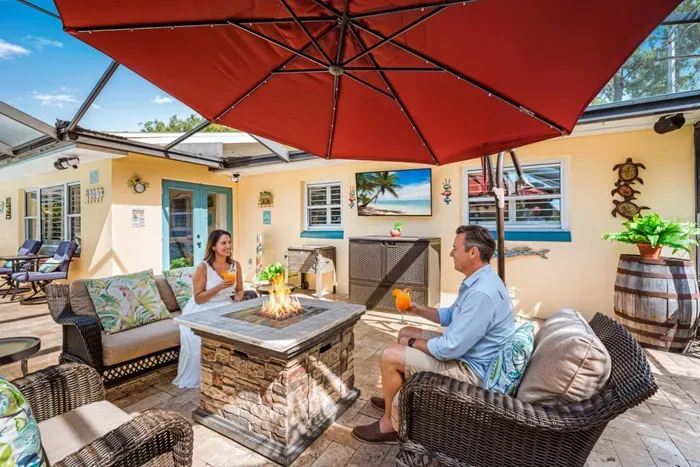 A warm, inviting outdoor retreat designed for relaxing, reconnecting, and enjoying the Florida lifestyle—complete with comfortable lounge seating, a cozy fire table, and plenty of shade for laid-back afternoons or evening cocktails.