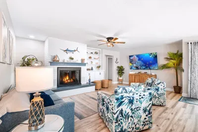 The spacious coastal living room features comfortable group seating, nautical details, a fireplace, and a 75-inch Smart TV for movie nights, game days, and relaxing after the beach.