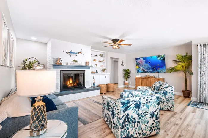 The spacious coastal living room features comfortable group seating, nautical details, a fireplace, and a 75-inch Smart TV for movie nights, game days, and relaxing after the beach.