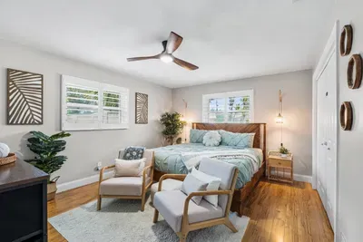 Palm Paradise, the primary suite at Twin Oaks, features a king bed, quality linens, tropical coastal styling, a Smart TV, and a private ensuite with an oversized walk-in rain shower.