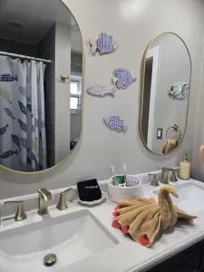 A bright, coastal-inspired bathroom filled with thoughtful details and a touch of whimsy. Double sinks provide plenty of space to get ready, while charming seaside décor, convenient toiletries, because even the little spaces should feel special.