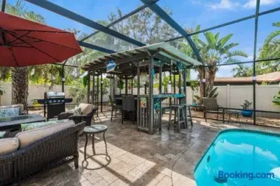 Screened pool patio with tiki bar, grill, and tropical lounge seating