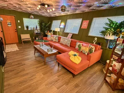 Retro-chic lounge with coral sectional, disco accents, and bright natural light