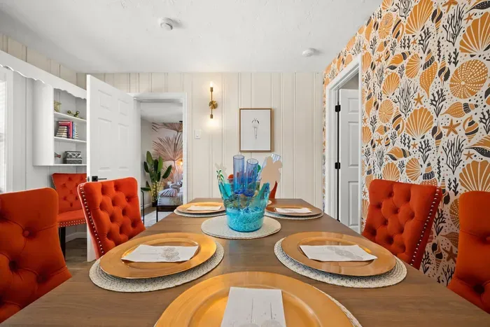 Dining table with gold charger plates and seashell wallpaper — steps from the primary suite. 4-bedroom pool rental, St. Pete, FL.