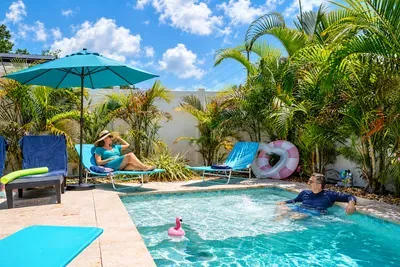 Private tropical pool oasis with loungers, shade, and lush palms