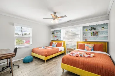 Two full beds with luxury bedding and yellow frames, ocean wave wallpaper, built-in shelving, and dedicated desk. 4-bedroom vacation rental, St. Petersburg, FL.