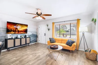 Bright modern living room with large TV, sunny window, and stylish seating