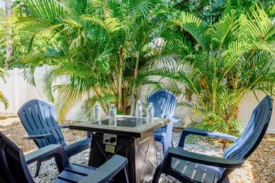 Fully fenced tropical backyard with a private pool, lounge seating, propane fire pit, propane grill, and space for families and friends to relax together.