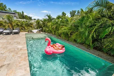 Full backyard overview — outdoor dining for 6, lounge chairs with pool noodles, private pool, and giant Connect Four. Gulfport/St. Pete, FL.