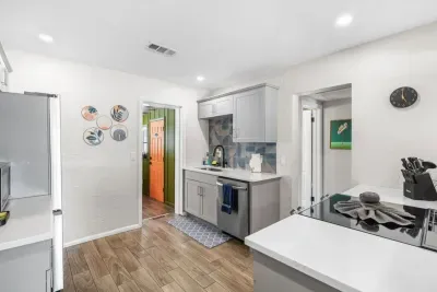 Kitchen — stainless dishwasher, geometric tile backsplash, grey shaker cabinets, full-size refrigerator. 4-bedroom vacation rental, St. Pete, FL.