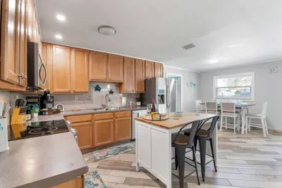 Fully equipped kitchen at Sun Oasis with stainless appliances, warm wood cabinetry, butcher-block island, and playful sea-turtle accents — everything a group needs to cook in style.