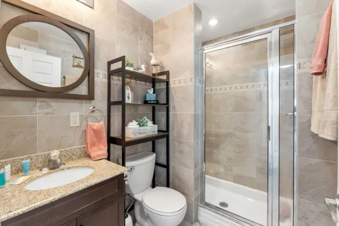 Warm-toned hall bathroom at Sun Oasis — neutral tile, granite vanity, glass walk-in shower, and charming seagull accents. Serves Bedrooms 2 and 3.