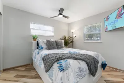 Bright queen bedroom with quality linens, a Smart TV, ceiling fan, large closet, and abundant natural light—a peaceful retreat after a day at the Gulf beaches.