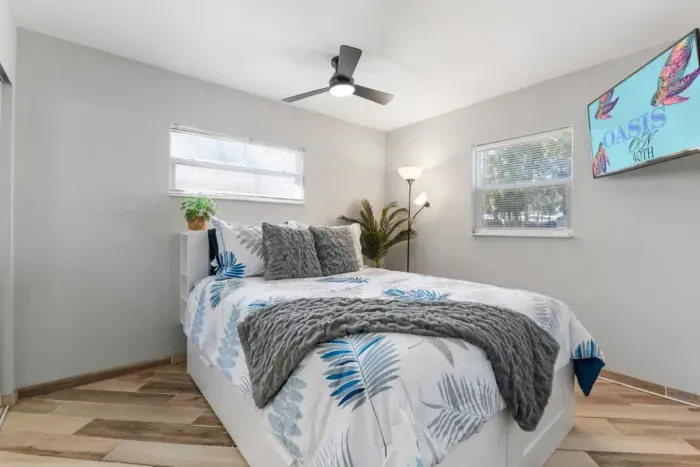 Bright queen bedroom with quality linens, a Smart TV, ceiling fan, large closet, and abundant natural light—a peaceful retreat after a day at the Gulf beaches.
