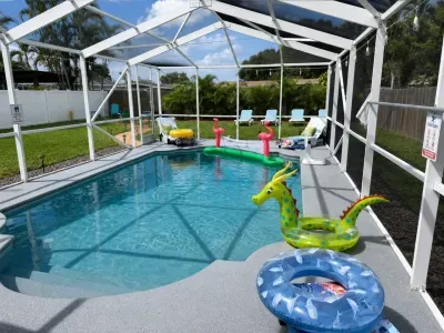 Screened-in private pool at Sun Oasis, a vacation rental in St. Petersburg, FL — crystal-clear water, lounge chairs, and lush tropical landscaping in a fully fenced backyard.