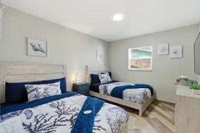 Sea-inspired bedroom with two full beds, quality linens, coastal shell artwork, and a large closet—ideal for children or additional guests.