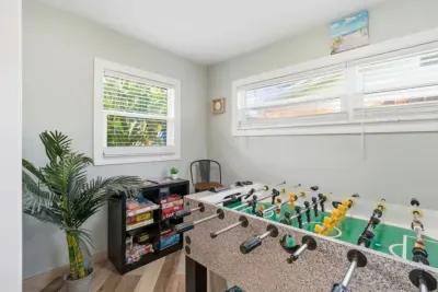 Sun Oasis game room featuring a full-size foosball table, board games, and coastal beach decor — a dedicated space for family fun steps from the living room.