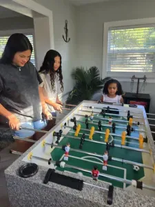 Guests enjoying the foosball table in the game room of this family-friendly vacation rental in St. Petersburg, FL — fun for all ages, steps from the pool.