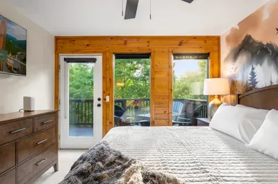 Cozy king bedroom with private deck access and peaceful wooded views