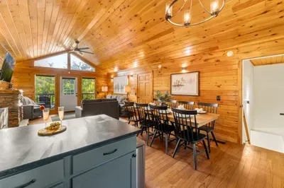 Cozy open-concept cabin with vaulted ceilings, dining for six, and deck access