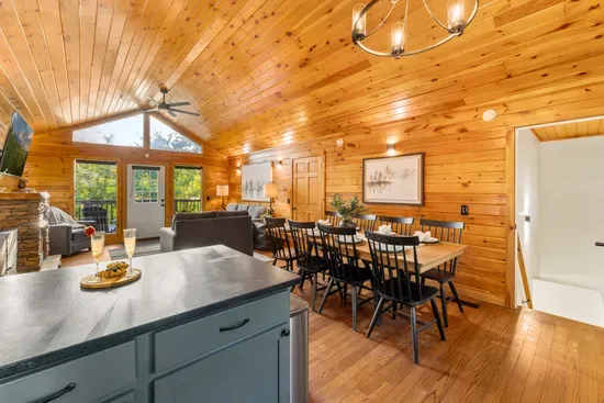Cozy open-concept cabin with vaulted ceilings, dining for six, and deck access