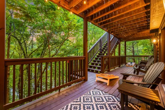 Covered forest-view deck with Adirondack seating and cozy string lights
