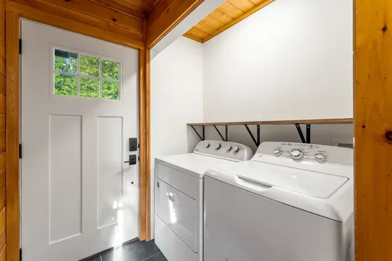 Bright laundry nook with full-size washer/dryer and warm wood accents
