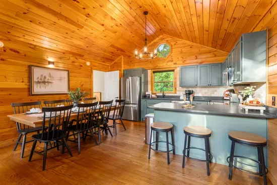 Warm cabin kitchen with vaulted wood ceilings, island seating, and dining for 8