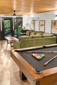Cozy lounge with pool table, plush seating, and warm cabin-style charm