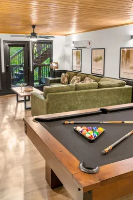 Cozy lounge with pool table, plush seating, and warm cabin-style charm