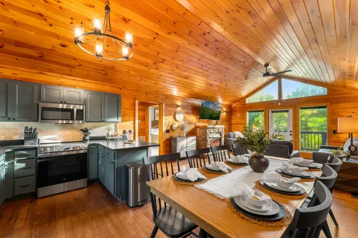 Warm cabin great room with chef’s kitchen, fireplace, and scenic windows