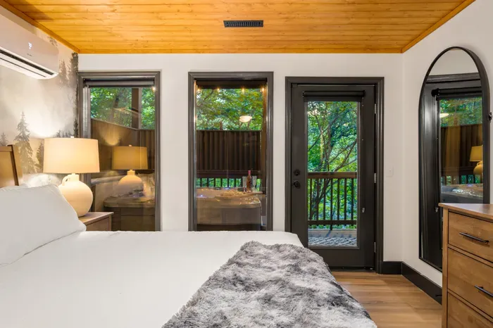 Cozy bedroom with forest views, private balcony, and hot tub