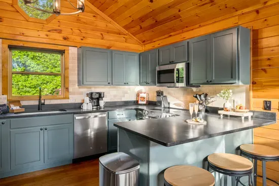 Bright cabin kitchen with island seating, modern finishes, and forest views