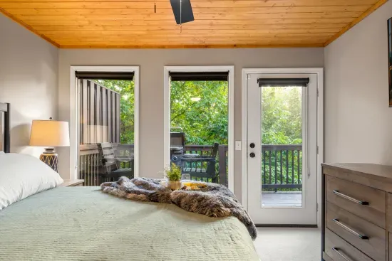 Bright bedroom with private deck access and serene wooded views