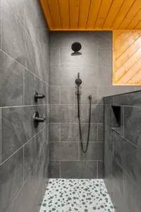 Spa-style walk-in shower with rainfall head, wood ceiling, and modern tile