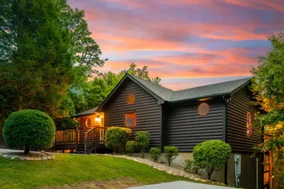 Cozy log cabin with sunset views, lush landscaping, and a welcoming porch