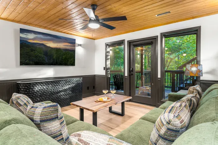 Cozy lounge with forest-view deck access and warm cabin-style charm