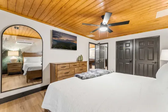 Cozy king bedroom with wood ceilings, large mirror, and modern touches