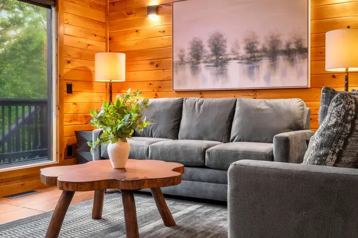 Cozy wood-paneled living room with plush seating and peaceful forest views