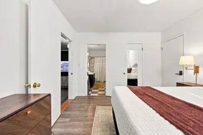 Bright, clean bedroom with ensuite bathroom access and warm wood accents