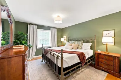 Cozy, elegant bedroom with king bed, warm lighting, and rich green walls