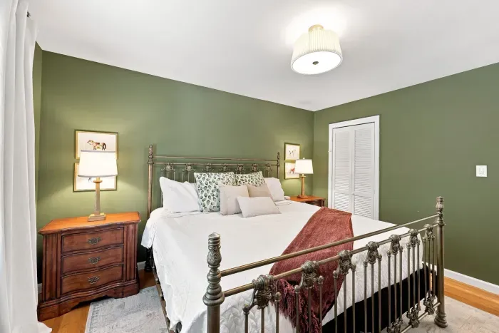 Cozy king bedroom with elegant décor, warm lighting, and rich green walls