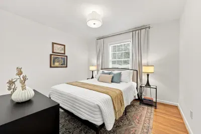 Bright, cozy bedroom with plush bedding, hardwood floors, and soft lighting