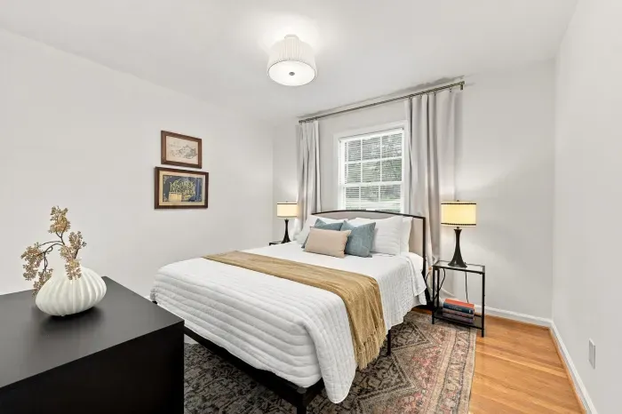 Bright, cozy bedroom with plush bedding, hardwood floors, and soft lighting