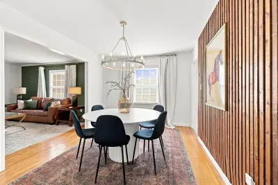 Bright dining room with designer lighting and warm wood accent wall